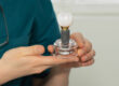 Dentist holding a dental implant in his hands, the dental implant model is oversized to see the details.